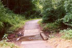 The trail crosses a side stream on columns.