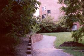 The trail curves to the left and a building appears on the right.  Do not take the intersecting trail to the left.