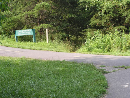 A paved trail crosses to the bicycle trail.  Continue straight on the dirt trail next to the Twin Branches trail sign.