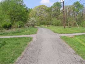 An asphalt trail crosses the service road.  Turn right to follow this trail back to the starting point parking lot.