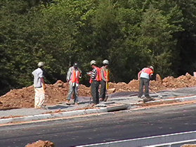 Workers are preparing the foundation for a sidewalk.